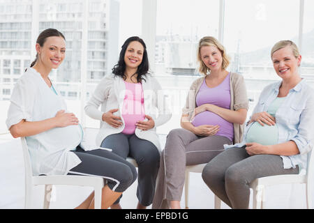 Schwangere Frauen sitzen zusammen an eine vorgeburtliche Klasse lächelnd Stockfoto