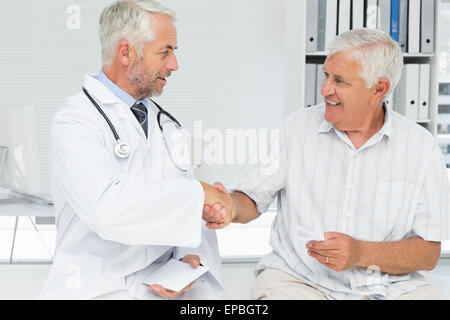 Lächelnde ältere Patient und Arzt Händeschütteln Stockfoto