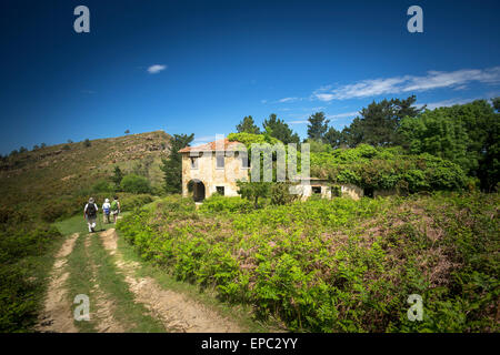 Wanderer, vorbei an einem verlassenen Haus Efeu bewachsenen (Guipúzcoa - Spanien). Randonneurs passant Devant Une Maison abandonnée Stockfoto