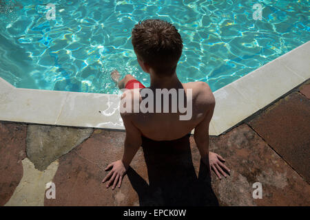 Ein Teenager liegt am Rande eines Swimmingpools mit den Füßen im Wasser bei Pells Pool, dem ältesten im freien öffentlichen Süßwasserpool im Vereinigten Königreich, in Lewes, East Sussex, England. Stockfoto