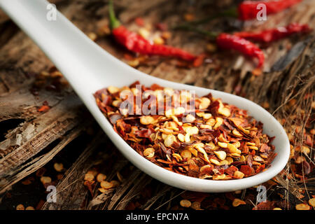 Zerkleinerten Chili Gewürz in einem weißen Löffel auf Holz Stockfoto