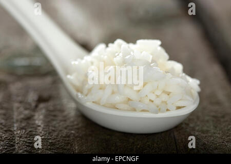 Löffel voll Reis über hölzerne Hintergrund Stockfoto