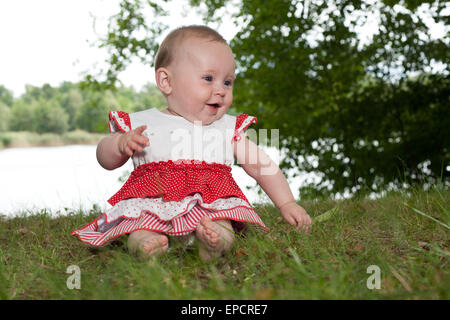 Kleines Mädchen sitzt und spielen am See Stockfoto