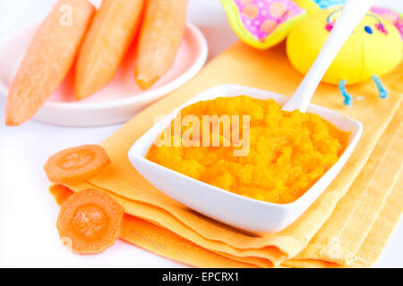 Babynahrung (pürierte Karotten) hautnah auf weißen Tisch Stockfoto