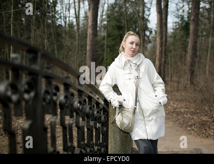 die junge Frau auf der Brücke im Park im zeitigen Frühjahr Stockfoto