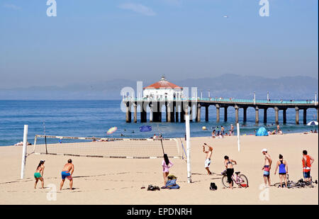 Männer und Frauen spielen Volleyball auf Manhattan Beach Kalifornien mit dem Pier im Hintergrund Stockfoto