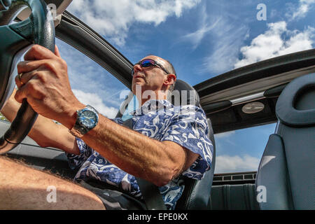 Ein Mann mittleren Alters mit einem Cabrio Auto mit dem Dach unten im Sommer in London, England, Großbritannien Stockfoto