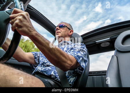 Ein Mann mittleren Alters mit einem Cabrio Auto mit dem Dach unten im Sommer in London, England, Großbritannien Stockfoto