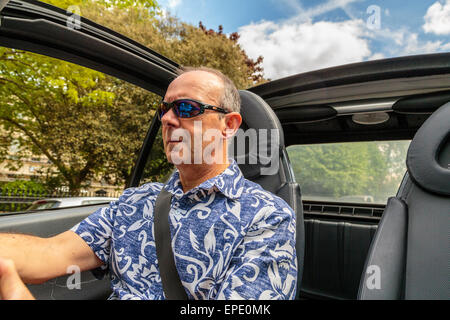 Ein Mann mittleren Alters mit einem Cabrio Auto mit dem Dach unten im Sommer in London, England, Großbritannien Stockfoto