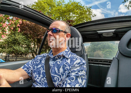 Ein Mann mittleren Alters mit einem Cabrio Auto mit dem Dach unten im Sommer in London, England, Großbritannien Stockfoto