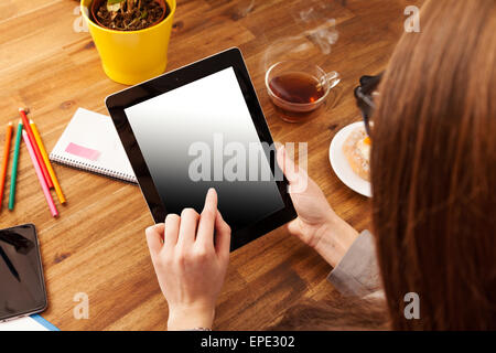 Junge Frau mit Tablet auf hölzernen Schreibtisch mit leeren Bildschirm für Text platziert. Schuss aus Vogelperspektive Stockfoto