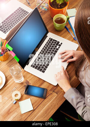 Junge Frau mit Laptop am Schreibtisch aus Holz mit leeren Bildschirm für Text platziert. Schuss aus Vogelperspektive Stockfoto