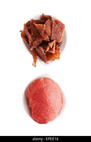 Dörrfleisch. Trocken und frisch Fleischstücke in zwei Schalen isoliert auf weißem Hintergrund, Ansicht von oben. Köstliche, kulinarische Fleisch zu essen. Stockfoto
