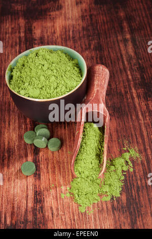 Grünen Nahrungsergänzungsmittel. Chlorella, Spirulina und Weizen Grass auf hölzerne Schaufel auf hölzernen Hintergrund. Alternative Medizin. Stockfoto