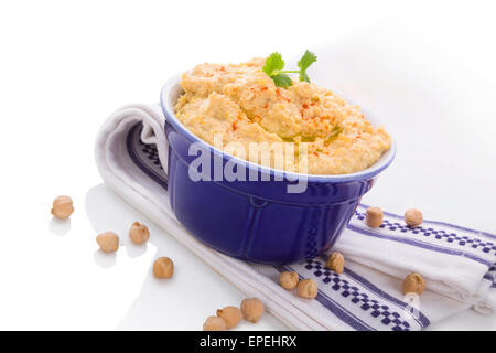 Köstliche Hummus in Keramiktopf auf weißen und blauen Tischdecke isoliert auf weißem Hintergrund. Traditionelle östliche Essen. Stockfoto