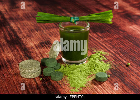 Grüne Supernahrungsmittel Chlorella, Weizengras, Gerstengras und Spirulina Tabletten, Pulver und Boden auf hölzernen Hintergrund. Detox. Stockfoto