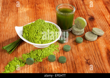 Detox. Chlorella Tabletten, Weizen Grass Pulver und grüne Getränk im Glas auf braunem Hintergrund aus Holz. Natürliche alternative Medizin Stockfoto