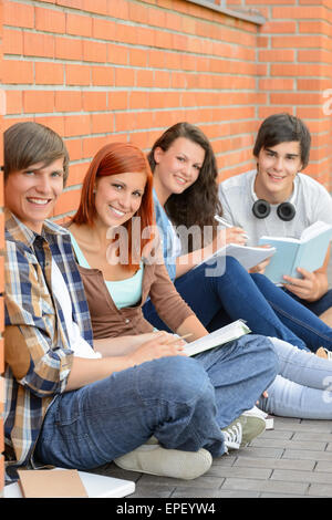 College-Studenten sitzen außerhalb von Mauer Stockfoto