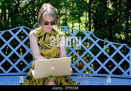 ältere Frau mit Laptop-Computer im Garten Stockfoto