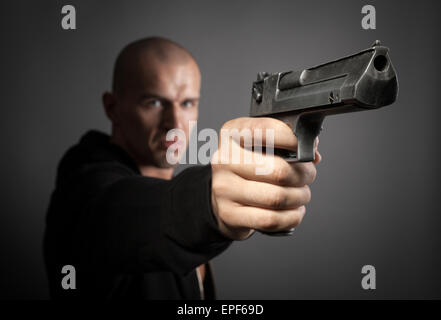 Mann Schießen Pistole auf grauem Hintergrund isoliert Stockfoto
