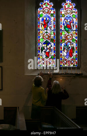 Frauen unter Glasfenster in der Kirche Kerzen anzünden Stockfoto