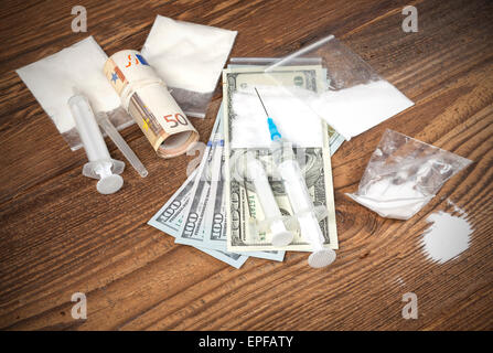 Drogen, Geld und Spritzen auf einem hölzernen Hintergrund. Stockfoto