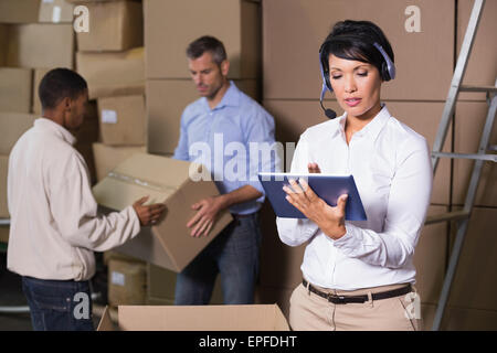 Hübsche Lagerleiter mit Tablet während hektische Zeit Stockfoto