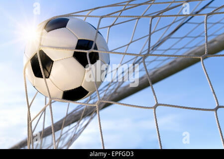 Fußball- oder Fußball Tor mit einem neutralen design Ball fliegen in die net, blauer Himmel und Sonne im Hintergrund Stockfoto