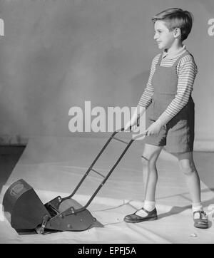 Schuljunge gesehen hier spielen mit einem Spielzeug Rasenmäher 2. Dezember 1957 Stockfoto