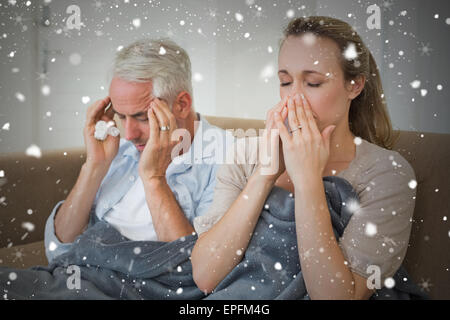 Zusammengesetztes Bild des Kranken paar sitzt auf der Couch unter einer Decke Stockfoto