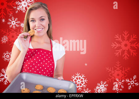 Zusammengesetztes Bild der hübschen Hausfrau zeigt heiße cookies Stockfoto