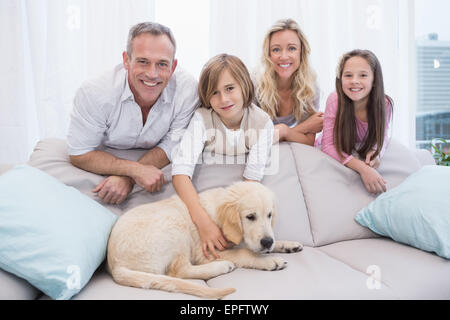 Welpen auf der Couch liegend mit der Familie hinter Stockfoto