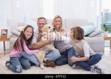 Lächelnde Familie mit ihrem Haustier gelbe Labrador auf dem Teppich Stockfoto