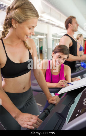 Trainer im Gespräch mit ihrem Kunden auf dem Laufband Stockfoto