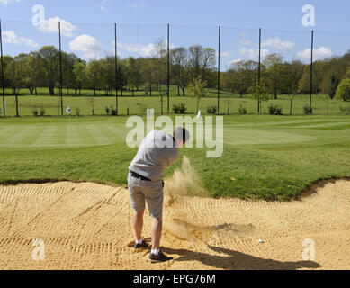 Männlichen Golfer spielen von einem Bunker auf dem Übungsgelände an der Sundridge Park Golf Club Bromley in Kent England Stockfoto