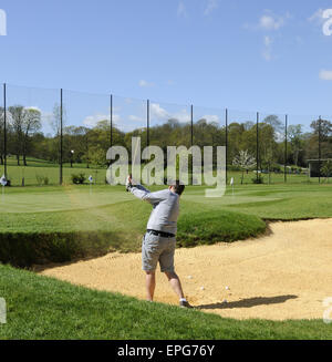 Männlichen Golfer spielen von einem Bunker auf dem Übungsgelände an der Sundridge Park Golf Club Bromley in Kent England Stockfoto