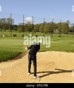 Männlichen Golfer spielen von einem Bunker auf dem Übungsgelände an der Sundridge Park Golf Club Bromley in Kent England Stockfoto