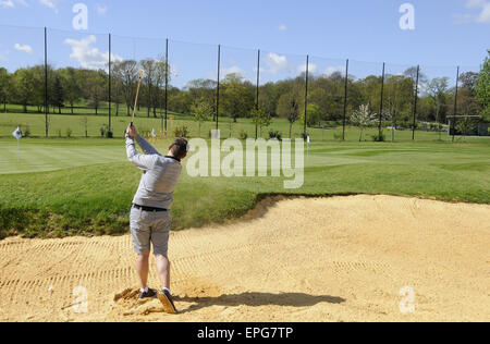 Männlichen Golfer spielen von einem Bunker auf dem Übungsgelände an der Sundridge Park Golf Club Bromley in Kent England Stockfoto