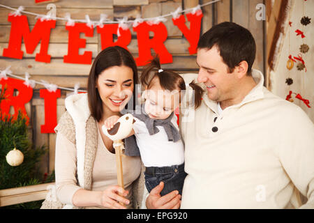 Familie mit einjährigen Tochter in der Nähe von Weihnachten Hintergrund Stockfoto