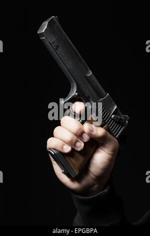 männliche Hand mit Gewehr auf schwarzem Hintergrund isoliert Stockfoto