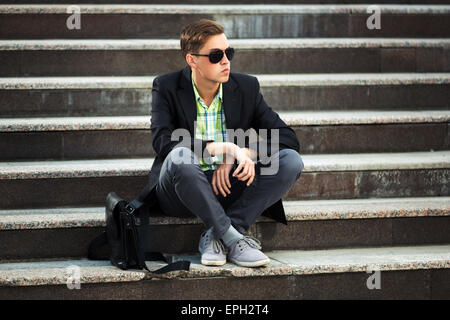 Junge Mode Mann sitzen auf den Stufen Stockfoto