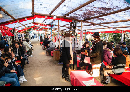 Menschen sitzen in Mänteln an Tischen während des New Year Festival in überdachten Outdoor-Essbereich am Nishinomiya Shinto-Schrein in japan. Stockfoto