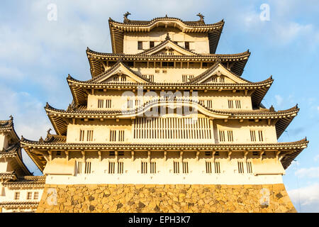 Der sonnenbeleuchtete Borogata-Stil halten des Himeji Schloss in Japan, während der Nachmittag goldene Stunde gegen einen blauen Himmel mit einigen weißen Wolken in. Stockfoto