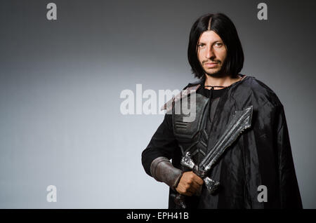 Böse Ritter mit Schwert vor einem dunklen Hintergrund Stockfoto