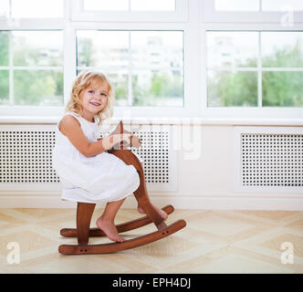 Kleine süße Mädchen im Kinderzimmer mit Holzpferd Stockfoto