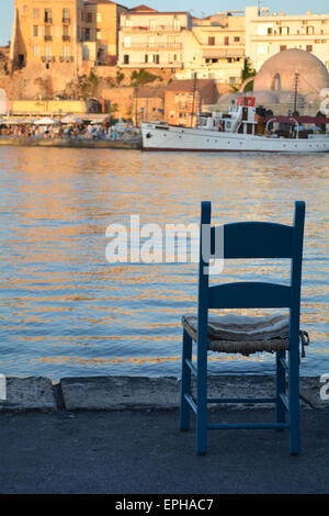 Einzelstuhl mit Blick auf den Hafen bei Sonnenuntergang in Chania, Kreta, Griechenland Stockfoto