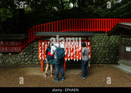 Menschen hängen will und Opfergaben von kleinen hölzernen Planken auf einem Fuchs-Ema am Fushimi Inari-Schrein in Kyoto gemacht. Stockfoto