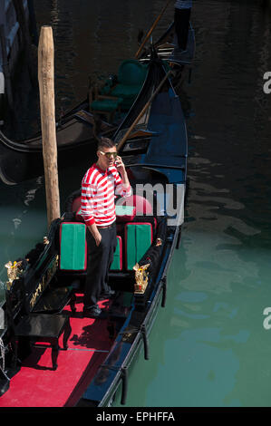 Venedig, Italien - 24. April 2013: Venezianischen Gondoliere im traditionellen rot-weiß gestreiften Hemd Gespräche über sein Handy. Stockfoto