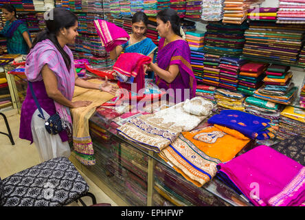 Einheimische Frau, die in einem Kleidung- und Stoffgeschäft mit farbenfrohen Materialien für Saris und lokale Kostüme wählt, Chennai, Tamil Nadu, Südindien Stockfoto