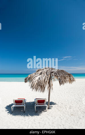 Paar leeren Strandstühle sitzen unter Palm Frond Palapa Dach auf eine leere Strecke der hellen Karibik-Strand in Varadero Kuba Stockfoto